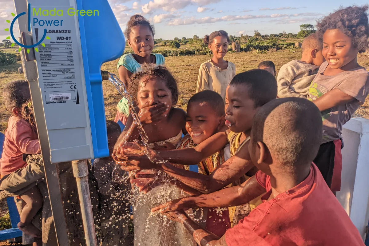 Un groupe d’enfants joyeux se rafraîchit avec de l’eau potable puisée grâce à un système à panneau solaire à Madagascar